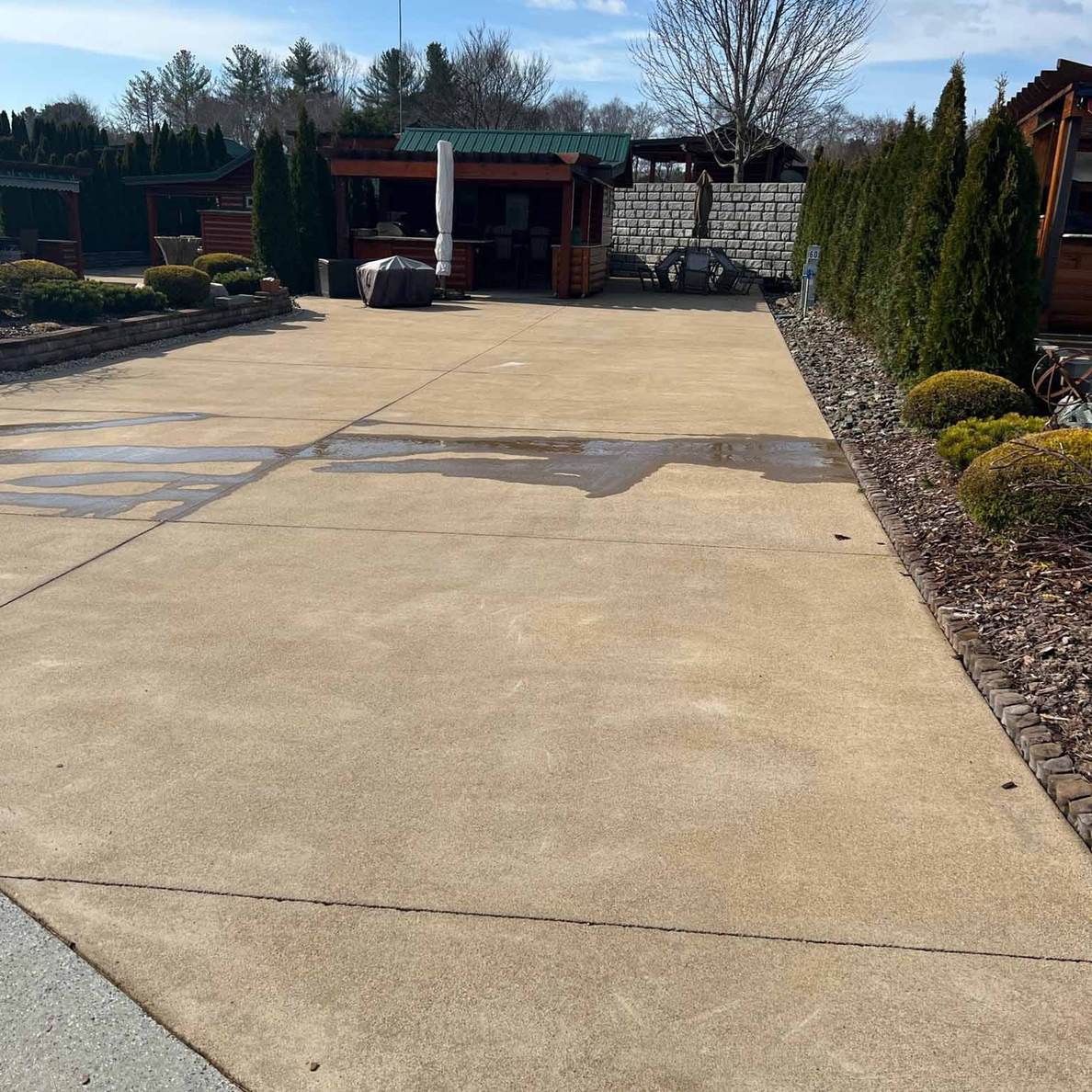 A wide clean concrete apron running up to a log building and a block retaining wall