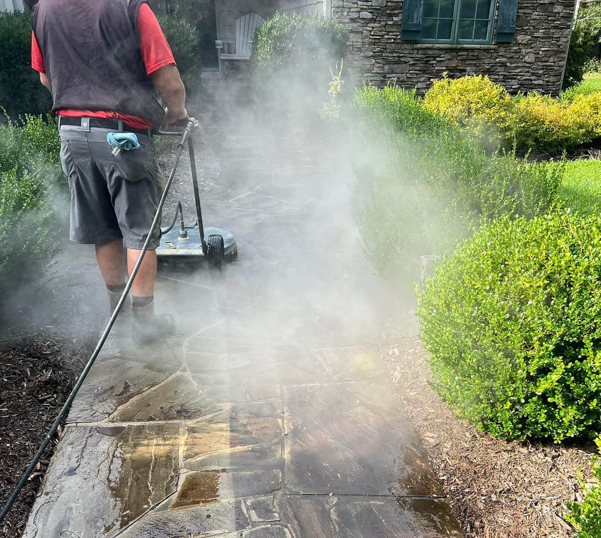 Running a surface cleaner along a stone walkway beside a home