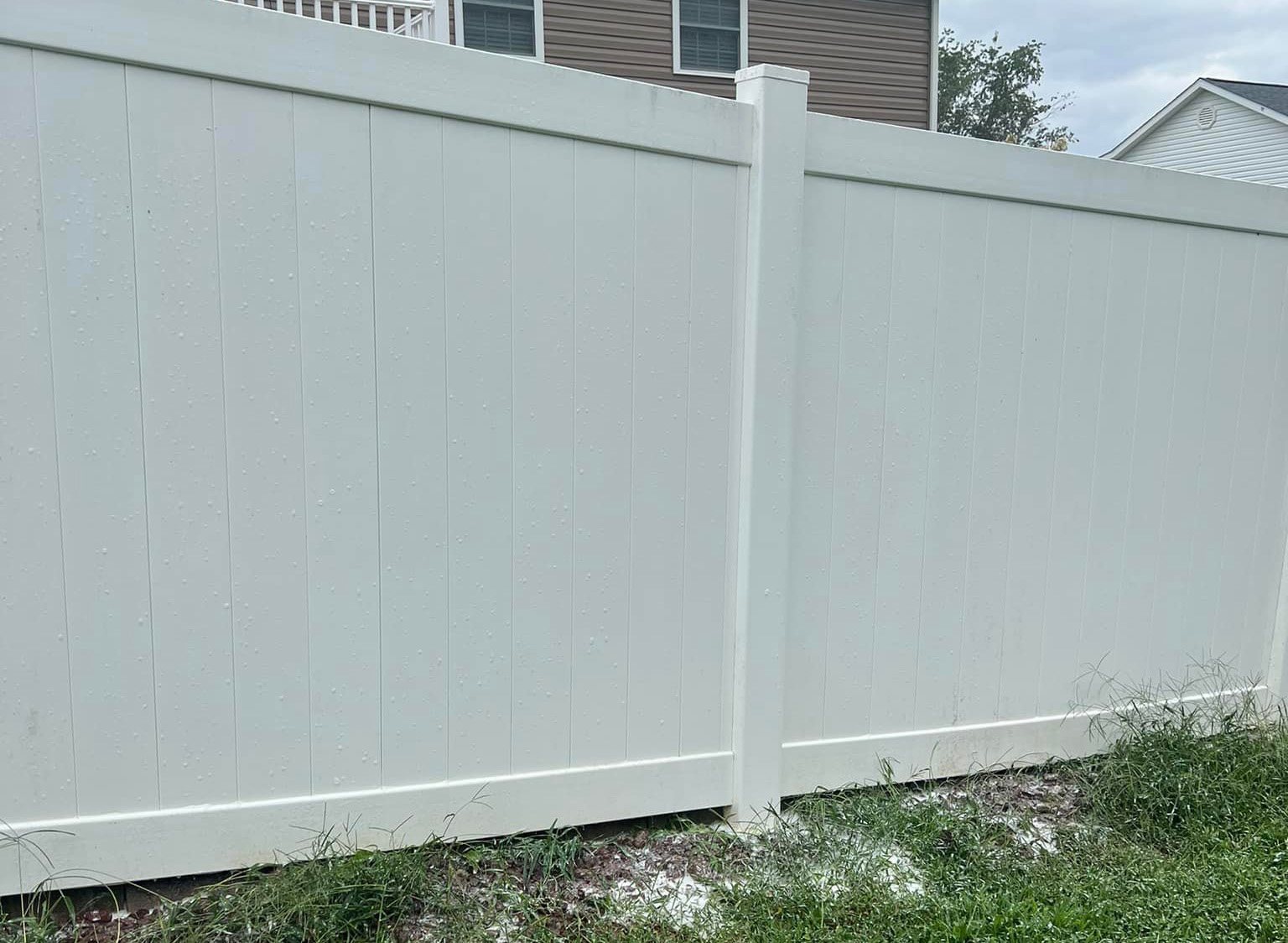 The same style of vinyl privacy fence after the wash, clean against the lawn