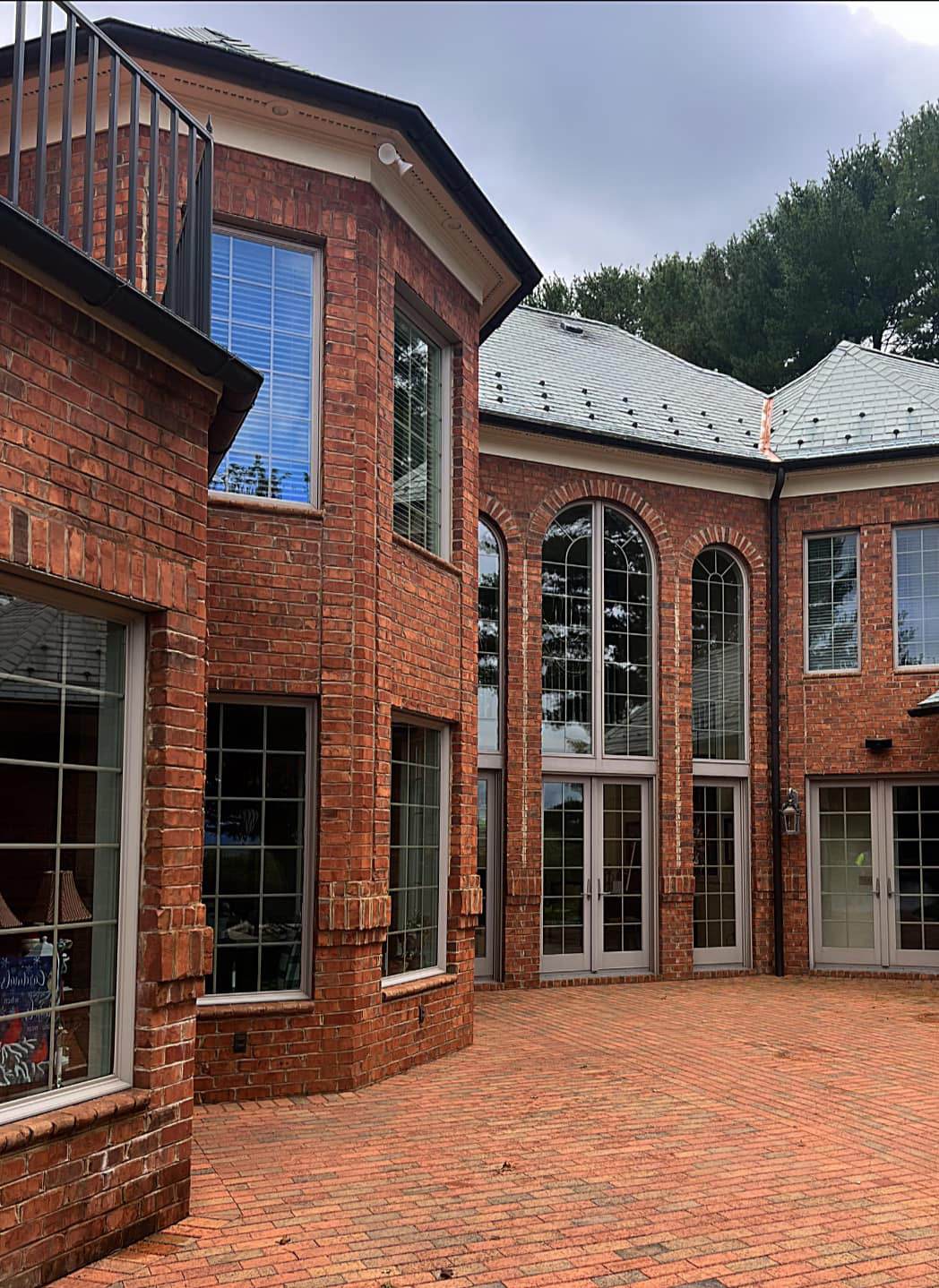 A brick home with arched windows above a clean brick paver courtyard
