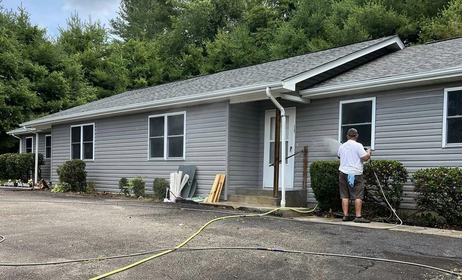 Washing the siding of a long ranch house from the paved driveway